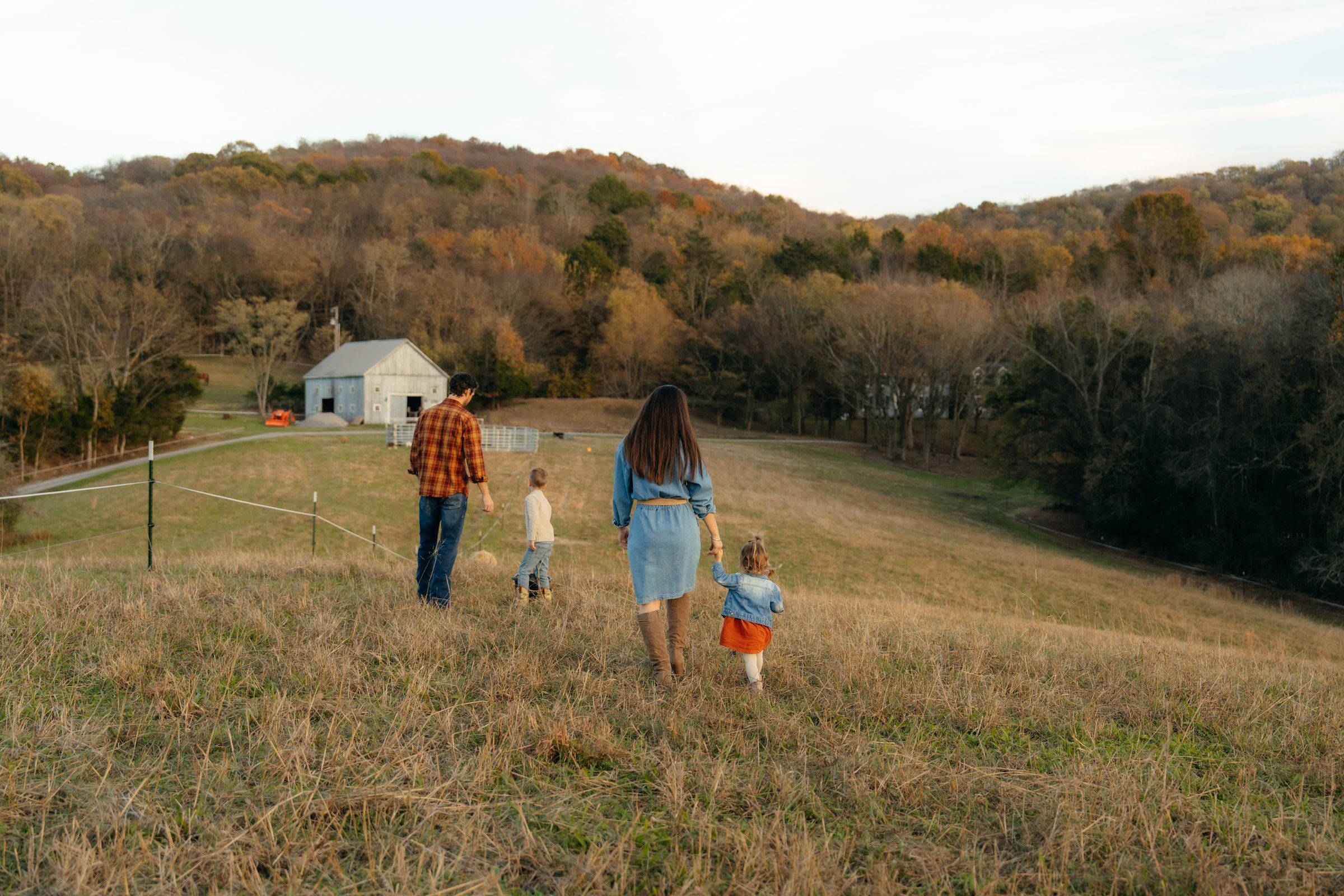 The Fast family walking across their pasture toward the wooded hills, a white barn in the distance
