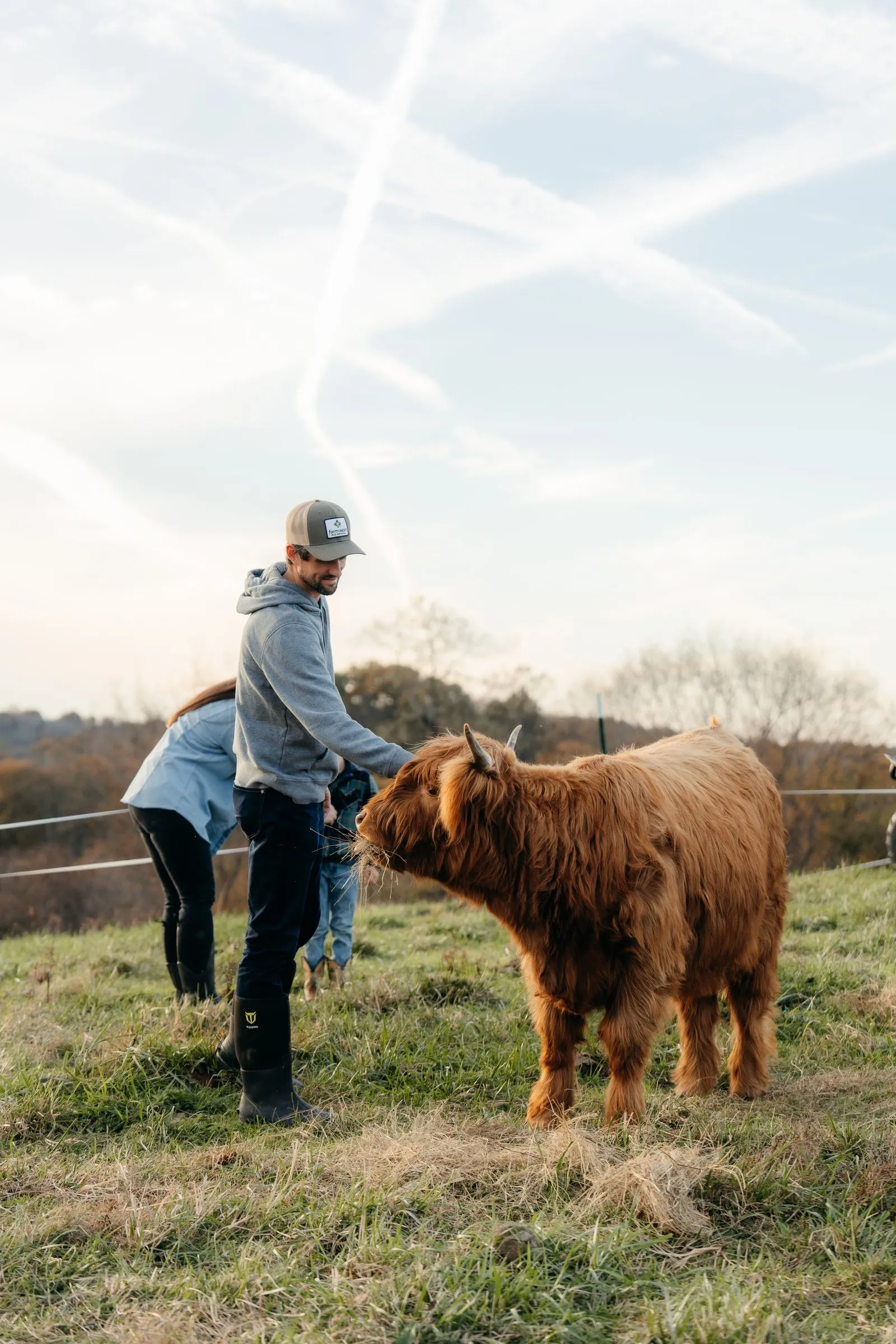 Rhett and his son stand with a red Highland in the pasture